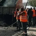 Construction workers in Vladivostok repairing roads with a dump truck unloading asphalt.