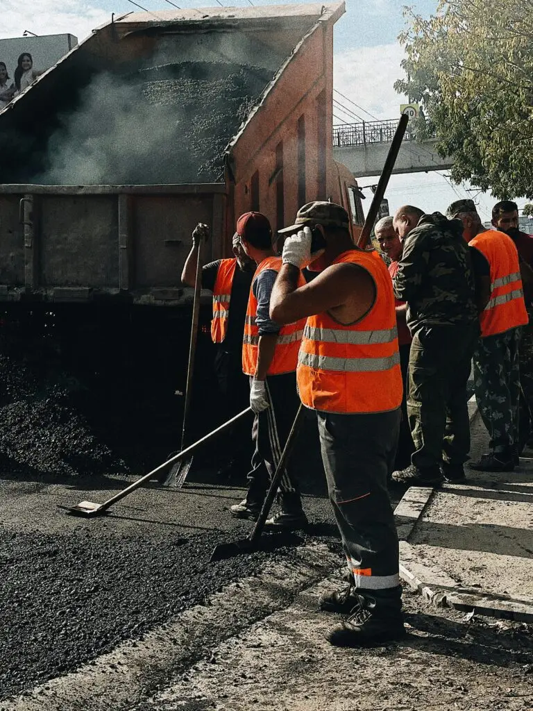 Construction workers in Vladivostok repairing roads with a dump truck unloading asphalt.