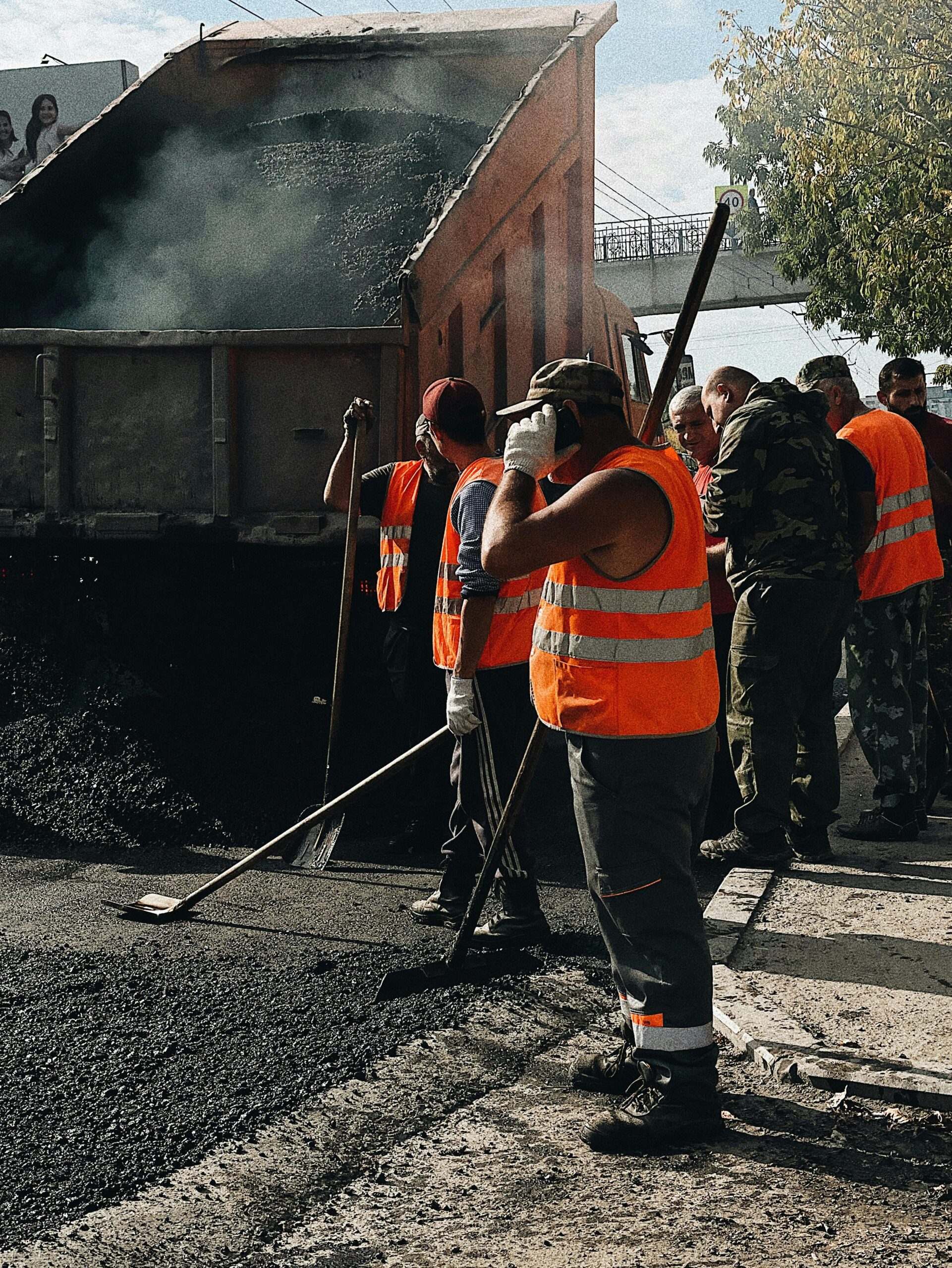 Construction workers in Vladivostok repairing roads with a dump truck unloading asphalt.
